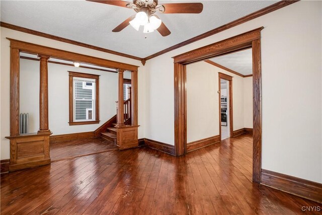 spare room featuring crown molding, radiator, decorative columns, and wood-type flooring