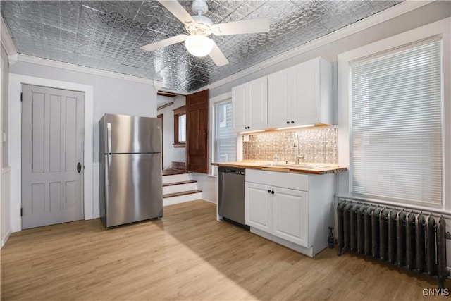 kitchen featuring radiator heating unit, an ornate ceiling, a sink, appliances with stainless steel finishes, and crown molding