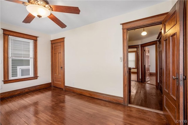 empty room with ceiling fan, baseboards, and wood finished floors