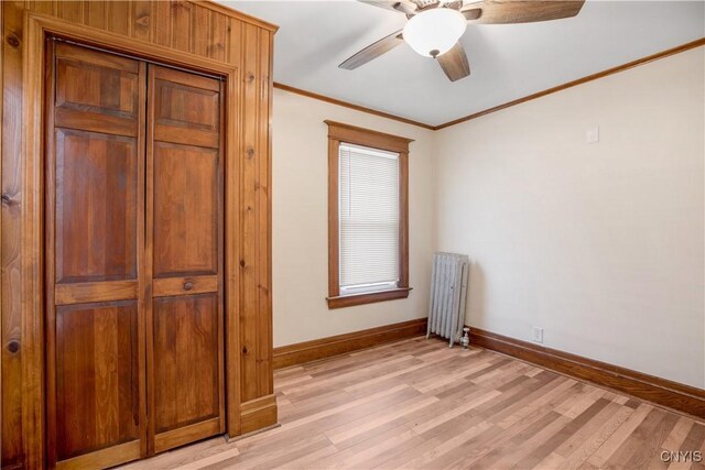 unfurnished bedroom featuring light wood-type flooring, radiator heating unit, baseboards, and ornamental molding