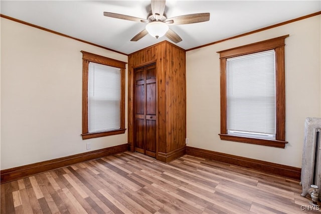 unfurnished bedroom featuring baseboards, radiator heating unit, light wood-style floors, and ornamental molding