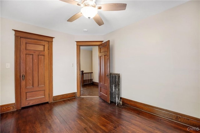 spare room featuring a ceiling fan, radiator heating unit, baseboards, and dark wood-style flooring