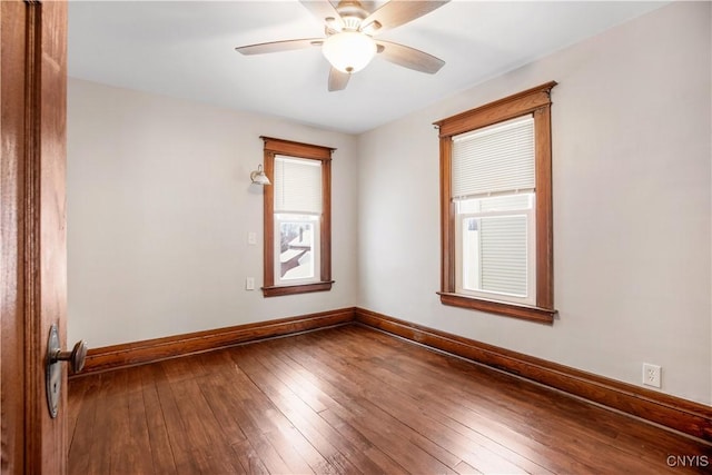 spare room with plenty of natural light, baseboards, and wood-type flooring