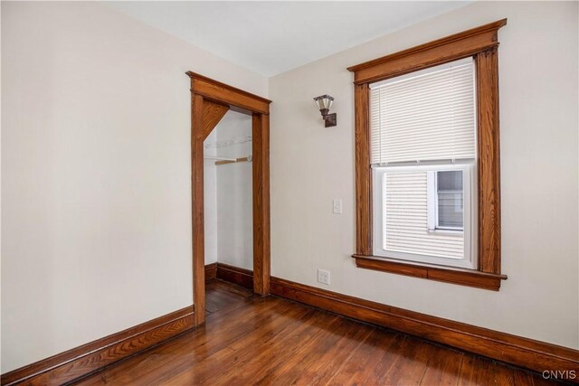 empty room with dark wood-type flooring and baseboards