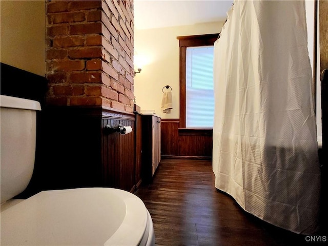 bathroom with a wainscoted wall, toilet, wooden walls, and wood finished floors