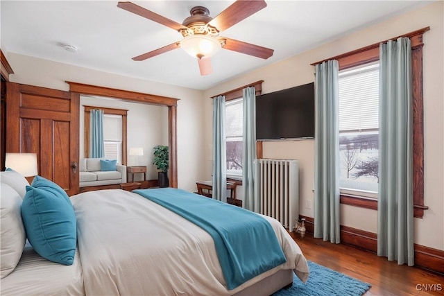 bedroom featuring radiator, wood finished floors, baseboards, and ceiling fan