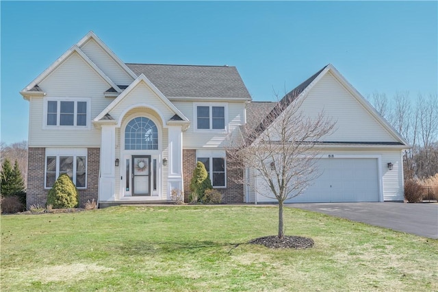 traditional home featuring a front yard, an attached garage, brick siding, and driveway