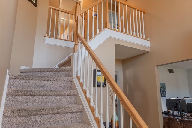 staircase featuring visible vents and a high ceiling