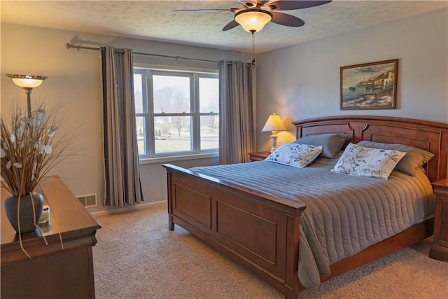 bedroom with baseboards, visible vents, ceiling fan, a textured ceiling, and light colored carpet