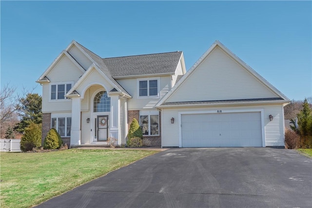 traditional home with aphalt driveway, brick siding, an attached garage, and a front yard