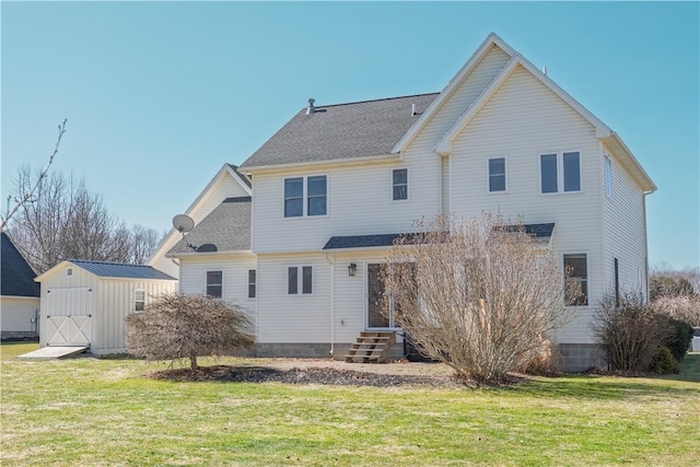 rear view of house featuring a shingled roof, entry steps, a lawn, an outdoor structure, and a storage unit