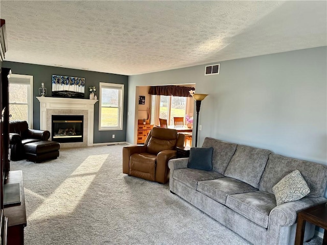 living room featuring visible vents, a textured ceiling, a fireplace, and carpet flooring