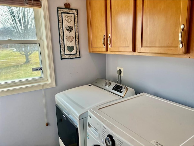 clothes washing area with a wealth of natural light, cabinet space, and washing machine and clothes dryer