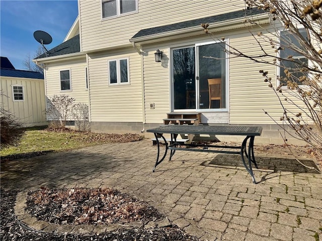 back of property with a patio area, entry steps, and a shingled roof