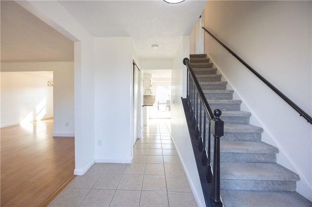 stairway with tile patterned floors and baseboards