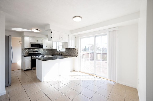 kitchen featuring a sink, decorative backsplash, dark countertops, and stainless steel appliances