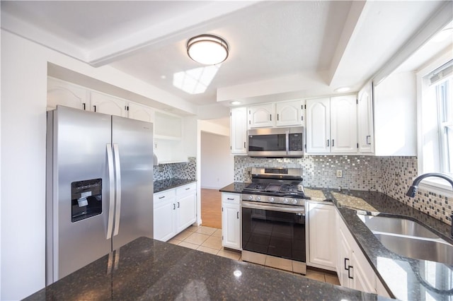 kitchen featuring a sink, stainless steel appliances, decorative backsplash, and dark stone counters