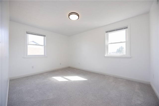 unfurnished room featuring carpet, a healthy amount of sunlight, and baseboards