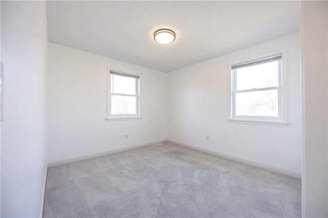 unfurnished room with baseboards and light carpet