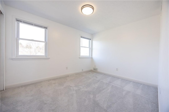 unfurnished room with light colored carpet, visible vents, and baseboards