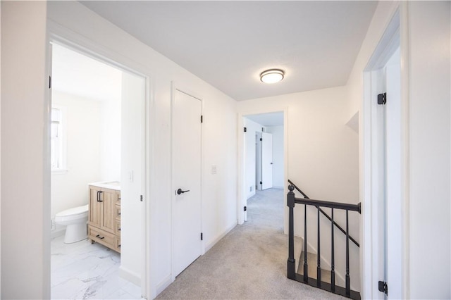 hallway with baseboards, an upstairs landing, and marble finish floor