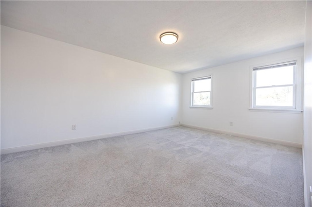 spare room with light carpet and baseboards