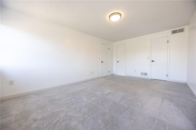 spare room with visible vents, light carpet, and baseboards