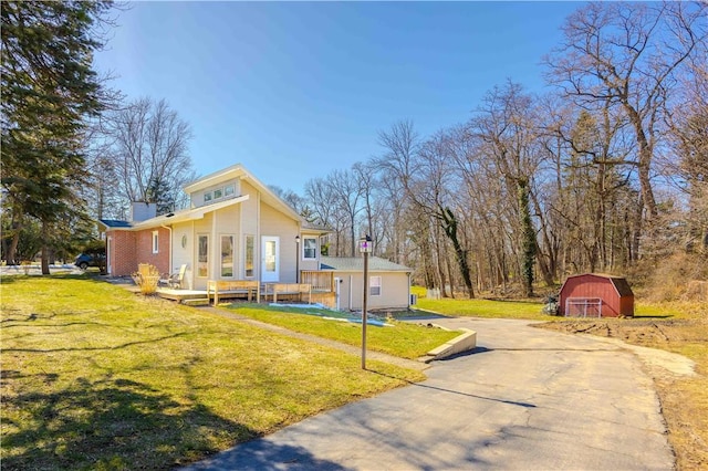 view of front of house featuring an outbuilding, driveway, a barn, a front yard, and a chimney