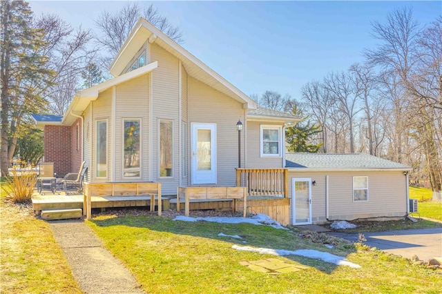 exterior space featuring central air condition unit, a lawn, and a wooden deck