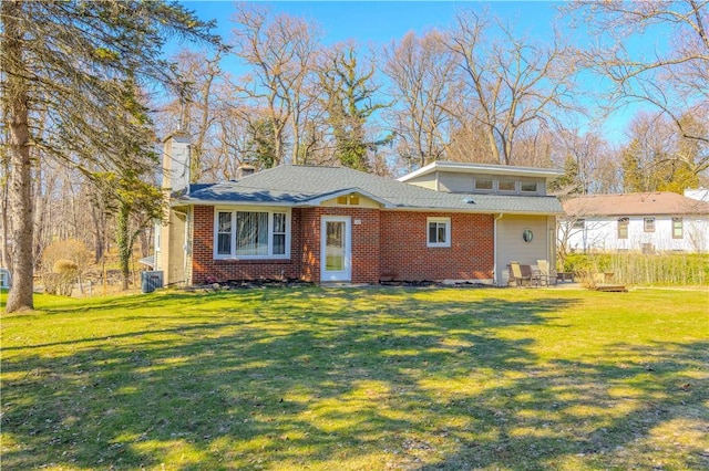 view of front of property featuring a front yard, brick siding, central AC, and a chimney