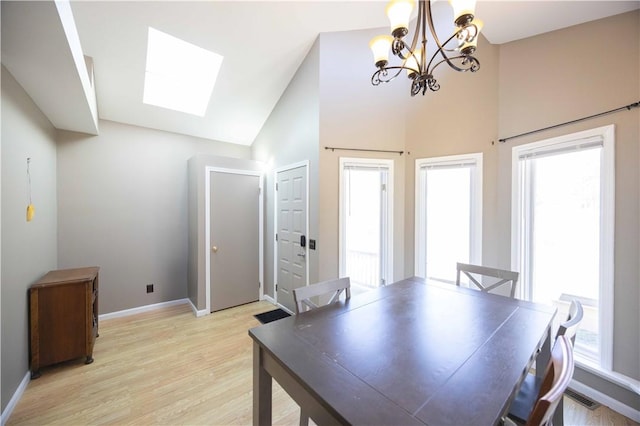 dining space featuring baseboards, visible vents, light wood finished floors, and high vaulted ceiling