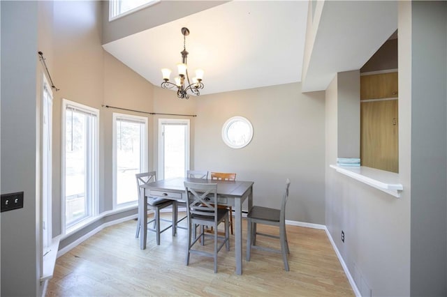 dining space with a chandelier, a high ceiling, light wood-type flooring, and baseboards