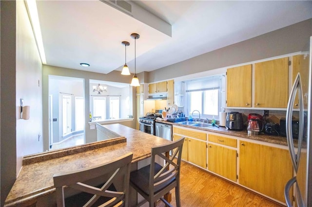 kitchen featuring visible vents, light wood finished floors, a sink, under cabinet range hood, and appliances with stainless steel finishes