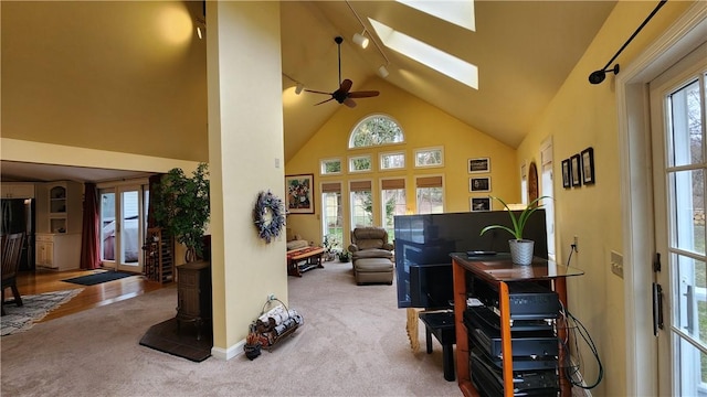 carpeted living area with high vaulted ceiling, a skylight, and ceiling fan