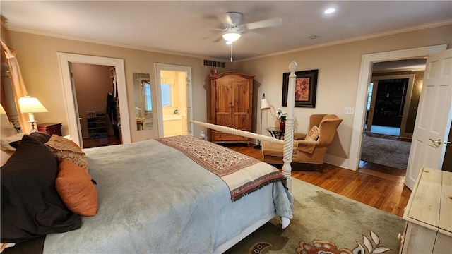 bedroom with a spacious closet, visible vents, crown molding, wood finished floors, and a closet