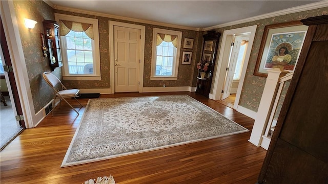 foyer featuring wallpapered walls, wood finished floors, and ornamental molding