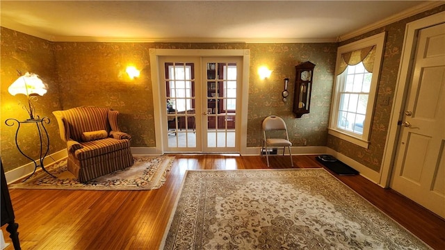 sitting room featuring wallpapered walls, crown molding, baseboards, and hardwood / wood-style flooring