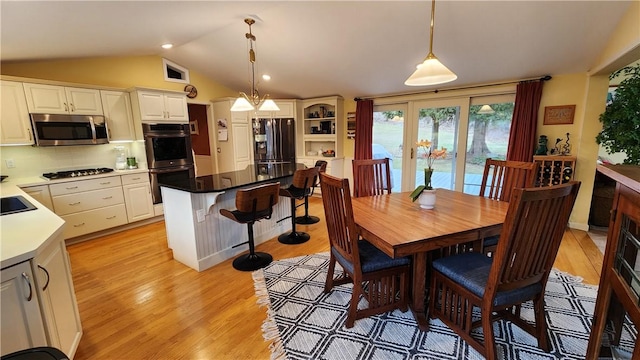 dining space with visible vents, lofted ceiling, and light wood-style floors