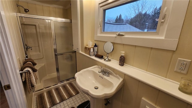 full bathroom with a shower with door and a sink