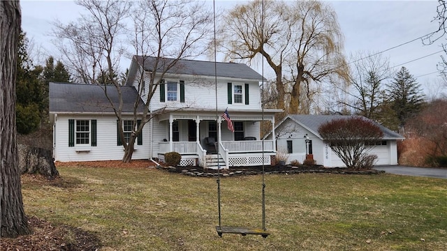 traditional-style home with aphalt driveway, a garage, covered porch, and a front lawn