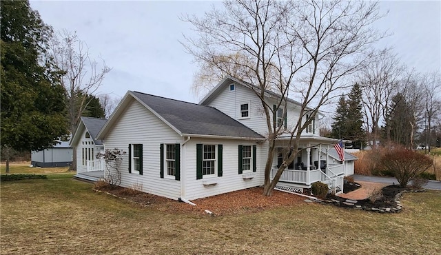 view of side of property featuring a porch, a yard, and roof with shingles