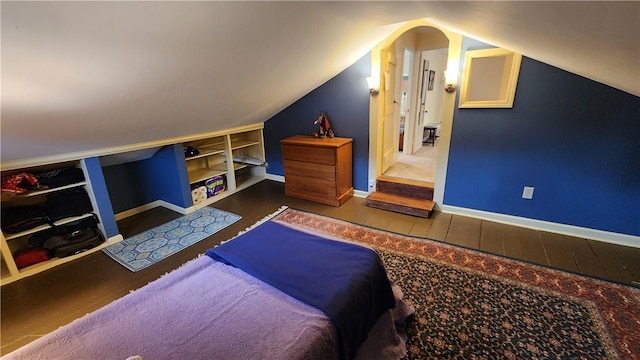 bedroom featuring baseboards, lofted ceiling, and wood finished floors