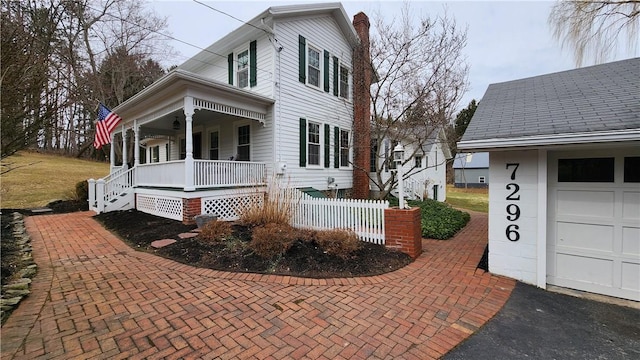 view of home's exterior featuring covered porch, a chimney, and a garage