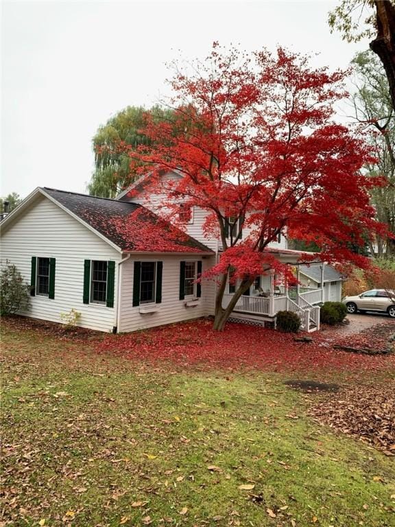 rear view of house featuring a yard and covered porch