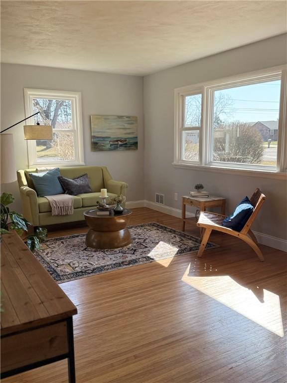 living room with visible vents, baseboards, and wood finished floors