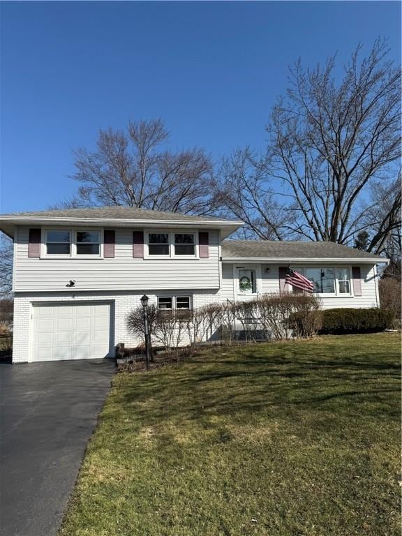 split level home featuring brick siding, a front yard, an attached garage, and driveway