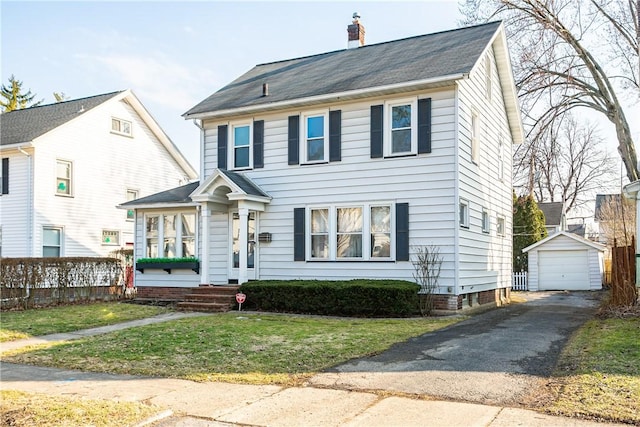 view of front facade featuring an outbuilding, a chimney, a front lawn, a garage, and aphalt driveway