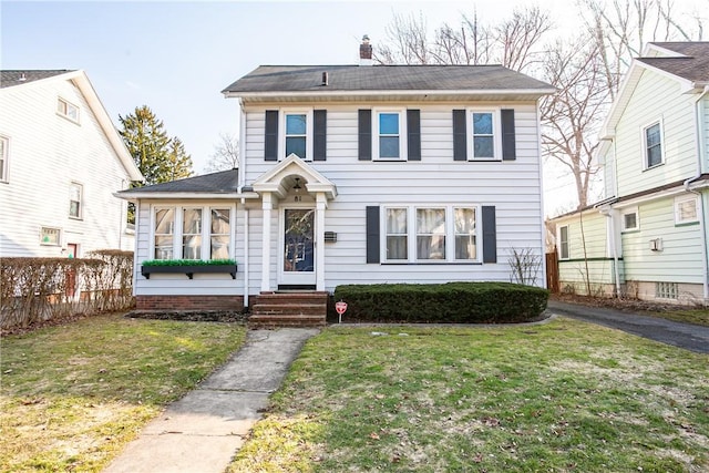 view of front facade with a front yard, fence, and a chimney