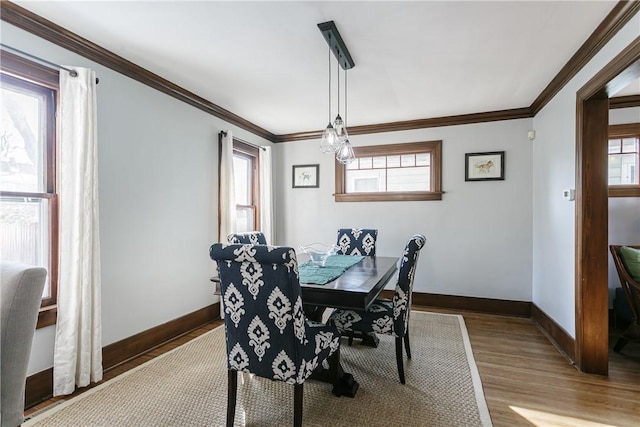 dining space featuring crown molding, baseboards, and wood finished floors