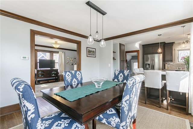 dining room with a healthy amount of sunlight, baseboards, light wood-style floors, and ornamental molding